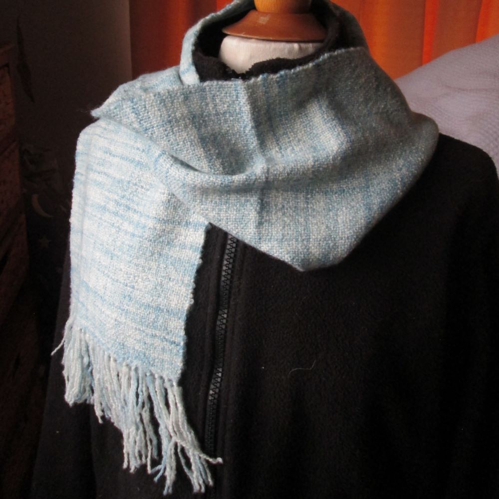 blue and cream randomly striped scarf wrapped around a black jacket on a mannequin