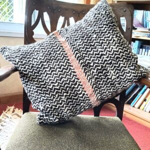 black and white cushion with a pink stripe on a chari