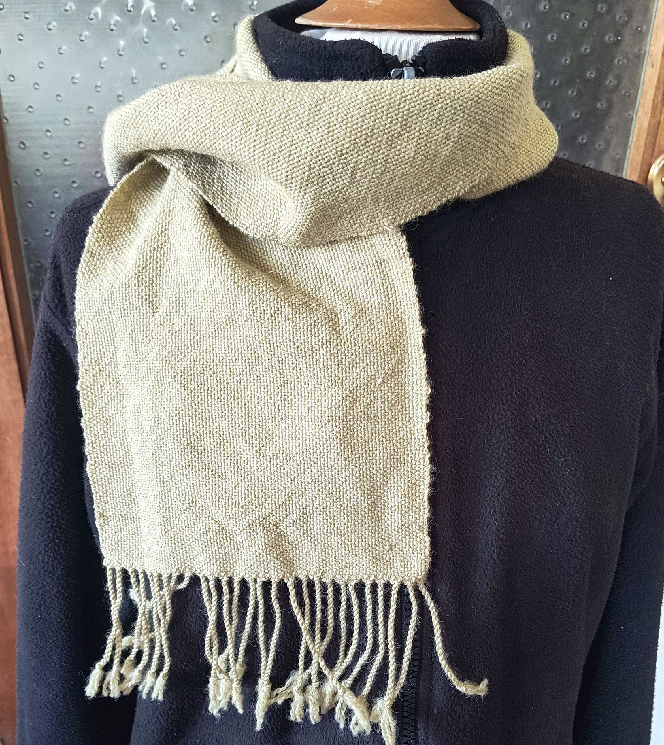 olive green scarf wrapped around the neck of a mannikin with black jacket